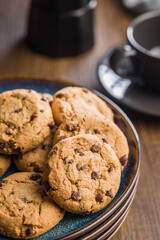 Chocolate chip cookies on plate on wooden table.
