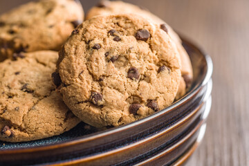 Chocolate chip cookies on plate on wooden table.