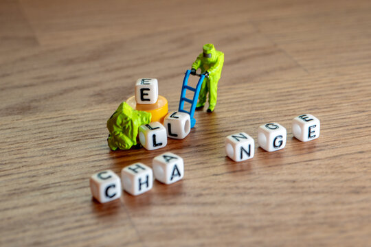 Removing white cubes with letters l and e of the word challenge creating new word change on wooden background with miniature figurines in hazmat biohazard suites