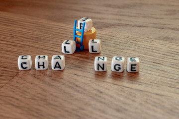 Removing white cubes with letters l and e of the word challenge creating new word change on wooden background