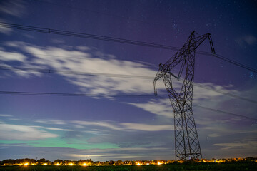 Aurora borealis in cloudy sky above transmission tower near Prague, October 10, 2024