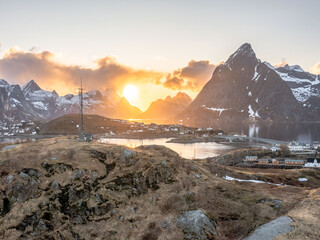 Sunset over snow capped mountains and ocean in Norway - shot on drone. 