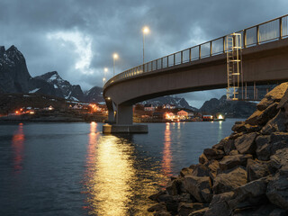 A bridge over a fjord in Norway at night with snow capped mountains. 