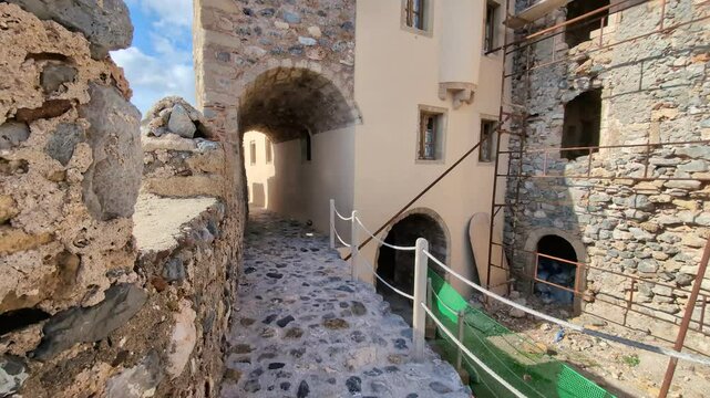 Walking through the charming streets of Monemvasia, Greece, under clear skies and bright sunlight