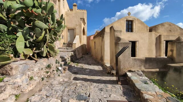 Walking through the charming streets of Monemvasia, Greece, under clear skies and bright sunlight