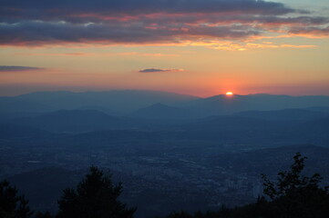 Fototapeta premium sunset over the city behind the mountains 