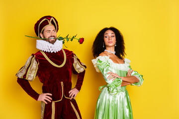 Couple in red and green renaissance-themed costumes posing against a vibrant yellow background