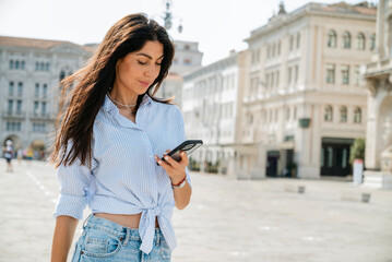 Fototapeta premium Beautiful young woman using her phone on the street in Italy 