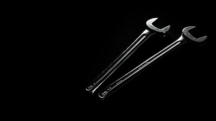 Shiny metal wrenches on black background: industrial precision tools with minimalistic design