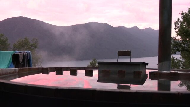 Ambiente tranquilo de tinaja caliente, con atardecer de colores, frente al lago Caburgua, Puc&oacute;n, Chile, 4K_1