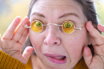 middle-aged mature woman with bulging eyes, face close-up, goggle eyes in fright, startled and...