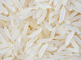 Close-up shot of dry, uncooked long grain basmati rice. Grains are slender and translucent, natural texture.