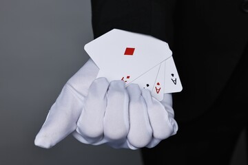 Illusionist taking playing cards out of sleeve on grey background, closeup