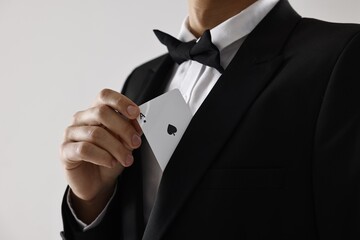 Illusionist hiding playing card behind jacket lapel on white background, closeup