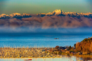 USA, Washington State, Seattle. Dawn on the Olympic Mountains that overlook a marina on the Puget...