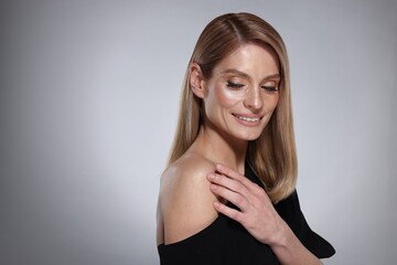 Fototapeta premium Portrait of beautiful happy woman with straight blonde hair and stylish makeup on grey background. Space for text
