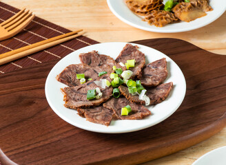 Beef Shank topped with green onion served in plate with fork and chopsticks isolated on wooden board side view of taiwan food