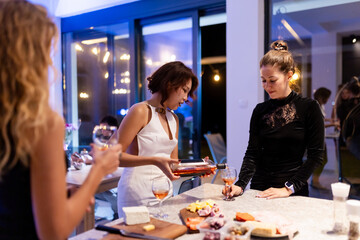 Friends enjoying a social evening gathering indoors with wine and snacks in a cozy and modern atmosphere