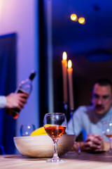 Cozy Evening with Candlelight, Glass of Wine, and Friendly Conversation at a Dinner Table
