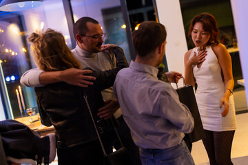 Group of friends greeting and sharing gifts at a festive evening gathering indoors