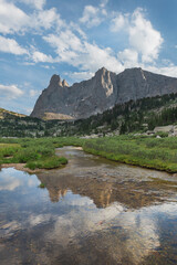 War Bonnet and Warrior Peaks reflected in stream flowing into Lonesome Lake in Cirque of the Towers. Popo Agie Wilderness, Wind River Range, Wyoming.