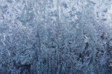 Frozen pattern of hoarfrost and frostwork structure on the glass. Color texture photo for background.