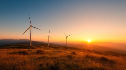 Obraz premium Experience the beauty of nature as the sun sets behind wind turbines, illuminating the mountains and highlighting the importance of alternative energy sources.