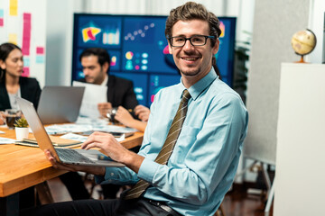 Portrait of businessman or analyst looking at camera with his colleague analyzing data analysis in...