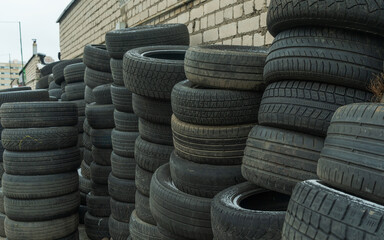 Obraz premium Storage of discarded old car tires outdoors, showcasing a pile of used tires ready for recycling. Highlighting environmental concerns and rubber waste management