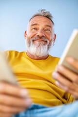 Portrait of a cheerful bearded mature man using mobile phone for online shopping and holding a credit card, isolated on a blue background