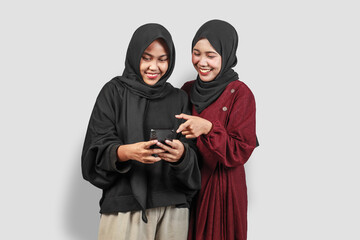 Two Happy Muslim Women in Hijab Using Smartphone and Smiling