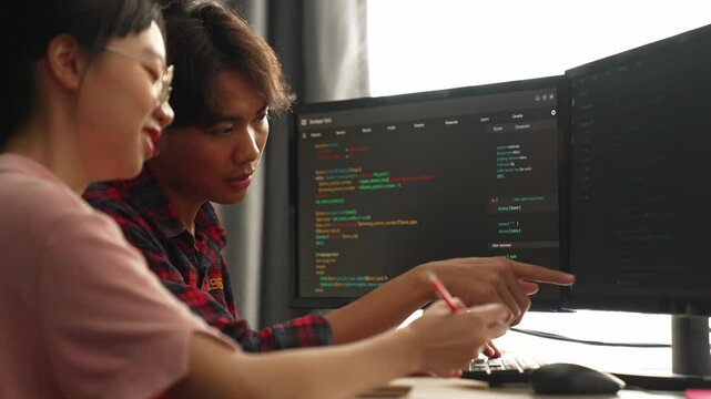 Slow motion back end software developer engineer for computer programming working together on debugging writing computing code, solving complex algorithms display on monitor in office. Burgeoning
