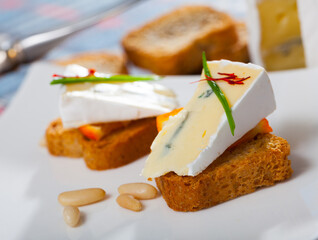 Tasty crostini with blue cheese, orange, decorated with chives and pine nuts