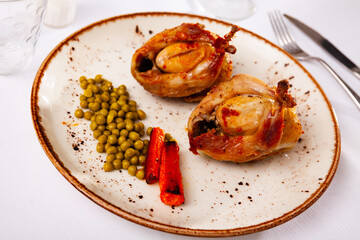 Traditional Spanish dish is two baked quails with carrots and canned peas
