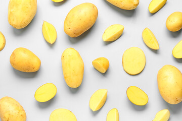 Whole and cut potatoes on blue background