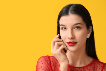 Fototapeta premium Beautiful young woman with red lipstick on yellow background