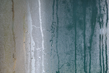Green and brown background texture of dripping water droplets on a fogged window