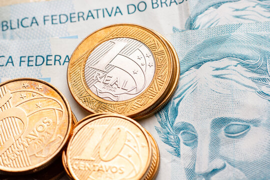 close em moeda de um real em cima de notas de cem reais