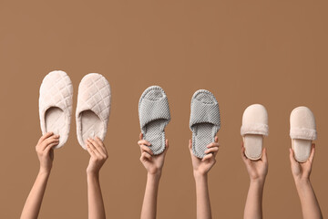 Female hands holding different slippers on beige background