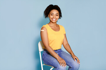 Flu vaccination concept. Young African American woman with plaster bandage after flu vaccine...