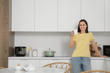 Young woman with cup in modern kitchen