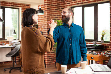 Businessman and woman in startup company high five near desk, displaying successful collaboration....
