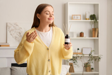 Young woman with reed diffuser at home