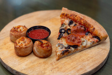Trozo de pizza con Rollitos de pepperoni con queso y salsa de tomate en un tabla de madera