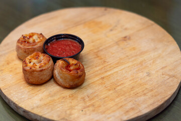 Rollitos de pepperoni con queso y salsa de tomate en un tabla de madera