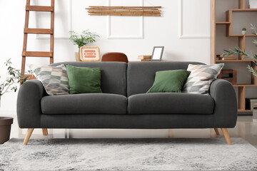 Cozy sofa, ladder, shelving unit and decorative olive tree in living room