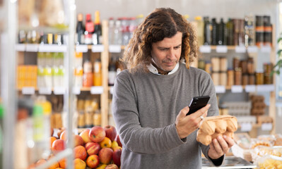 Male buyer scans QR code on packaging of chicken eggs label in a grocery store