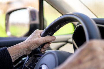 Close-up of a senior woman's hands holding the steering wheel while driving, capturing a moment of...