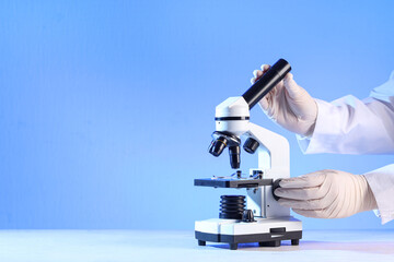 Scientist's hands with modern microscope on white table