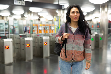 Young adult woman passenger walking in hall of subway station